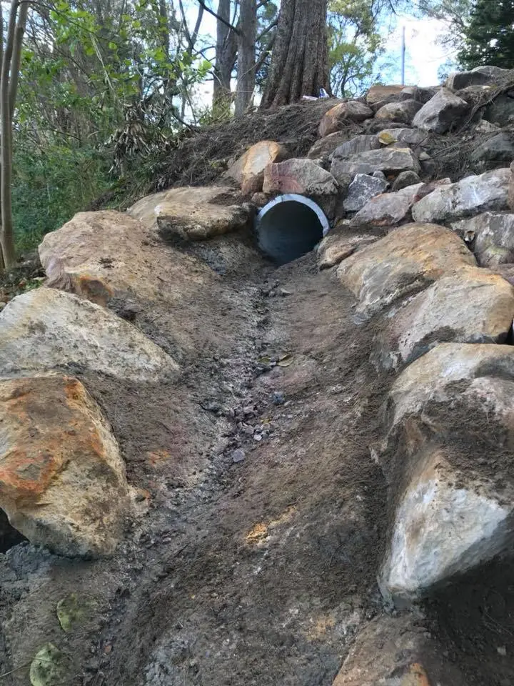 Rock-armoured stormwater outlet stabilising a bushland slope
